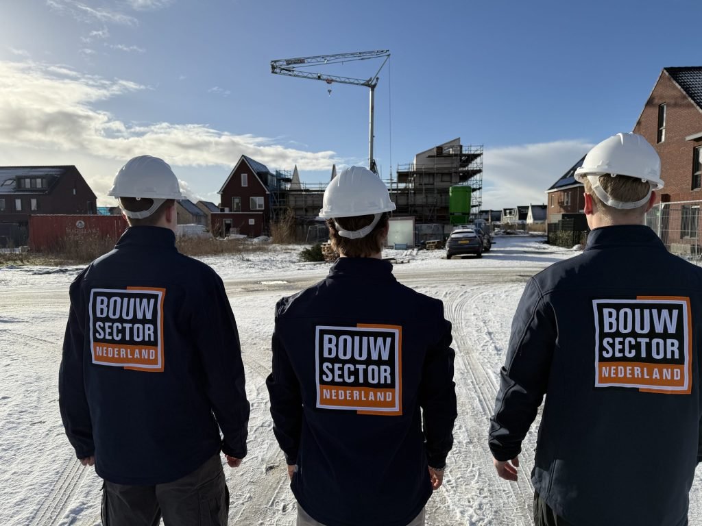 Drie medewerkers van Bouwsector Nederland met witte helm kijken naar een nieuwbouwstraat in aanbouw